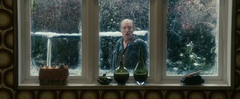 Movie still from “The Box” (2009), directed by Richard Kelly – A man standing in front of a window looking out at the snow; Medium shot, Over the shoulder angle