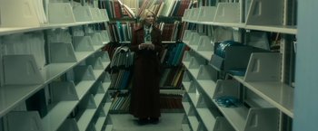 Movie still from “The Box” (2009), directed by Richard Kelly – A woman standing in front of a book shelf in a library; Wide shot, High angle