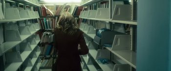 Movie still from “The Box” (2009), directed by Richard Kelly – A woman is standing in front of some books in a library; Medium shot, High angle