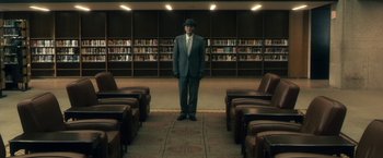 Movie still from “The Box” (2009), directed by Richard Kelly – A man in a suit and tie standing in a library; Wide shot, High angle