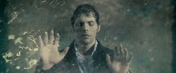 Movie still from “The Box” (2009), directed by Richard Kelly – A man with his eyes closed and his hands in the air in front of a window; Close Up shot, Overhead angle