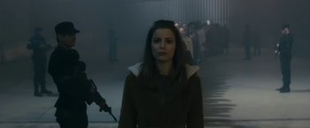 Movie still from “The Box” (2009), directed by Richard Kelly – A woman in a brown coat is standing in the fog; Medium shot, Over the shoulder angle