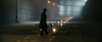Movie still from “The Box” (2009), directed by Richard Kelly – A man wearing a hat and a long coat walking down a street; Wide shot, Low angle