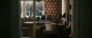 Movie still from “The Box” (2009), directed by Richard Kelly – A man sitting at a table in front of a window; Wide shot, High angle
