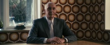 Movie still from “The Box” (2009), directed by Richard Kelly – An older man sitting at a table in front of a window; Medium shot, Low angle