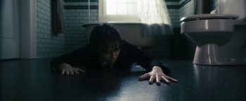 Movie still from “The Box” (2009), directed by Richard Kelly – A woman laying on the ground with her hands on the ground; Medium shot, High angle