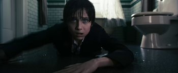 Movie still from “The Box” (2009), directed by Richard Kelly – A young man in a suit and tie is laying on a table; Close Up shot, High angle