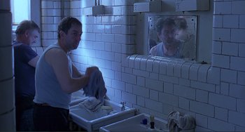 Movie still from “The Boxer” (1997), directed by Jim Sheridan – A man is washing his hands in the bathroom; Medium shot, Over the shoulder angle