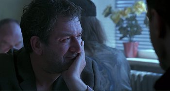 Movie still from “The Boxer” (1997), directed by Jim Sheridan – A person with his hand on his face; Close Up shot, Over the shoulder angle
