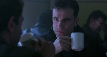 Movie still from “The Boxer” (1997), directed by Jim Sheridan – A man holding a coffee mug in his hands; Close Up shot, Over the shoulder angle