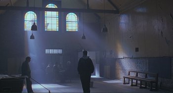 Movie still from “The Boxer” (1997), directed by Jim Sheridan – A person is standing in a room with a lot of light coming through the window; Wide shot, Low angle