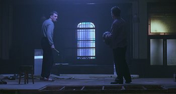 Movie still from “The Boxer” (1997), directed by Jim Sheridan – Two men are standing in a dark room; Wide shot, Low angle