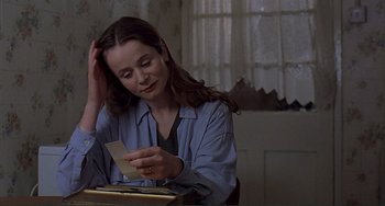 Movie still from “The Boxer” (1997), directed by Jim Sheridan – A woman sitting at a table holding a piece of paper; Close Up shot, Over the shoulder angle