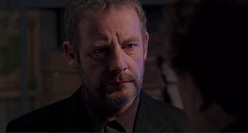 Movie still from “The Boxer” (1997), directed by Jim Sheridan – A person wearing a suit and tie; Close Up shot, Over the shoulder angle