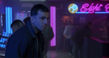 Movie still from “The Boxer” (1997), directed by Jim Sheridan – A man standing in front of a crowd of people; Medium shot, Over the shoulder angle