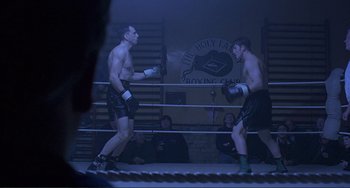 Movie still from “The Boxer” (1997), directed by Jim Sheridan – Two men in boxing gloves are facing each other in a boxing ring; Wide shot, Low angle