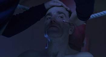 Movie still from “The Boxer” (1997), directed by Jim Sheridan – A man is getting his face waxed by a woman; Close Up shot, High angle