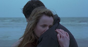 Movie still from “The Boxer” (1997), directed by Jim Sheridan – A man and a woman hugging on the beach; Close Up shot, Over the shoulder angle