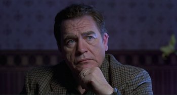 Movie still from “The Boxer” (1997), directed by Jim Sheridan – A person with his hand under his chin; Close Up shot, Low angle