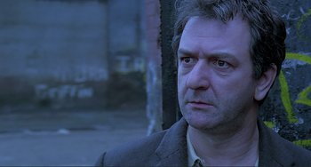 Movie still from “The Boxer” (1997), directed by Jim Sheridan – A person wearing a suit and tie; Close Up shot, Low angle