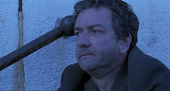 Movie still from “The Boxer” (1997), directed by Jim Sheridan – A person with a hammer on his head; Close Up shot, Low angle