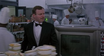 Movie still from “The Boxer” (1997), directed by Jim Sheridan – A man in a suit and bow tie in a restaurant kitchen; Medium shot, Low angle