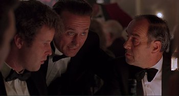Movie still from “The Boxer” (1997), directed by Jim Sheridan – A group of men sitting at a table talking; Close Up shot, Over the shoulder angle