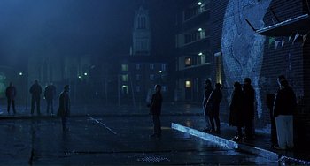 Movie still from “The Boxer” (1997), directed by Jim Sheridan – A group of people standing in the rain at night; Extreme Wide shot, Low angle