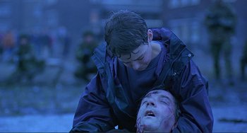 Movie still from “The Boxer” (1997), directed by Jim Sheridan – A young boy helping an older man who is lying on the ground; Medium shot, Low angle
