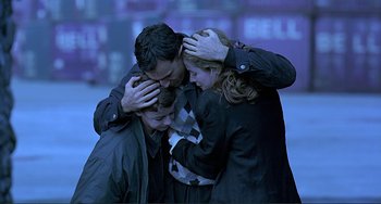 Movie still from “The Boxer” (1997), directed by Jim Sheridan – A group of three people hugging each other; Medium shot, High angle