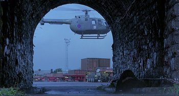 Movie still from “The Boxer” (1997), directed by Jim Sheridan – A helicopter flying through the air near a building; Extreme Wide shot, Low angle