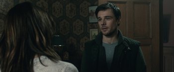 Movie still from “The Boy” (2016), directed by William Brent Bell – A man and a woman are standing in front of a wall; Close Up shot, Over the shoulder angle