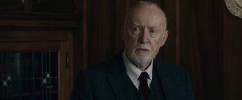 Movie still from “The Boy” (2016), directed by William Brent Bell – An older man wearing a suit and tie; Close Up shot, Over the shoulder angle