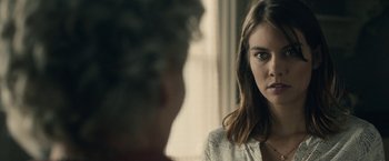 Movie still from “The Boy” (2016), directed by William Brent Bell – A woman is looking at a man in a room; Close Up shot, Over the shoulder angle