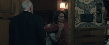 Movie still from “The Boy” (2016), directed by William Brent Bell – A woman holding a man's arm in a dark room; Medium shot, Over the shoulder angle