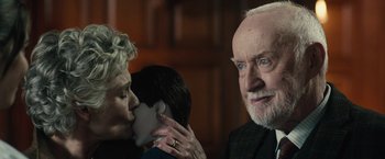 Movie still from “The Boy” (2016), directed by William Brent Bell – A man and a woman kiss on the cheek of a doll; Close Up shot, Over the shoulder angle