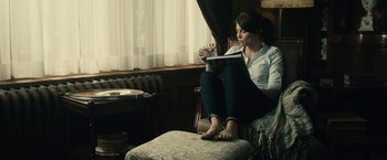 Movie still from “The Boy” (2016), directed by William Brent Bell – A woman sitting in a chair reading a book; Medium shot, High angle