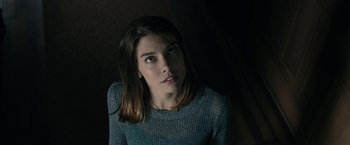 Movie still from “The Boy” (2016), directed by William Brent Bell – A young woman looking at the camera while wearing a sweater; Close Up shot, Low angle