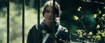Movie still from “The Boy” (2016), directed by William Brent Bell – A woman with a scarf standing behind a metal fence; Close Up shot, Low angle
