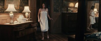 Movie still from “The Boy” (2016), directed by William Brent Bell – A woman standing in a room wearing a white towel; Wide shot, High angle