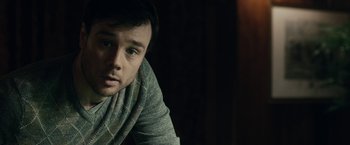 Movie still from “The Boy” (2016), directed by William Brent Bell – A man with a scarf around his neck looks at the camera; Close Up shot, Over the shoulder angle
