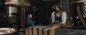 Movie still from “The Boy” (2016), directed by William Brent Bell – A woman and a boy in a room full of books; Medium shot, Over the shoulder angle