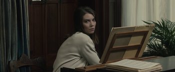 Movie still from “The Boy” (2016), directed by William Brent Bell – A woman sitting in front of an open book; Medium shot, Over the shoulder angle