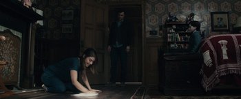 Movie still from “The Boy” (2016), directed by William Brent Bell – A woman laying on the floor in front of a man; Wide shot, Over the shoulder angle