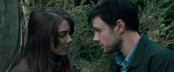 Movie still from “The Boy” (2016), directed by William Brent Bell – A man and a woman face to face in front of bushes; Close Up shot, Over the shoulder angle