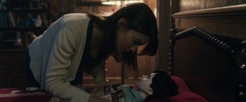 Movie still from “The Boy” (2016), directed by William Brent Bell – A young woman looking down at a doll laying on the floor; Close Up shot, Over the shoulder angle