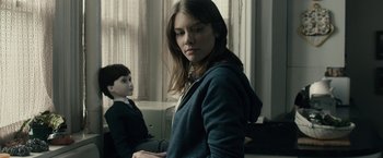 Movie still from “The Boy” (2016), directed by William Brent Bell – A young woman standing next to a young boy; Medium shot, Over the shoulder angle