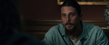Movie still from “The Boy” (2016), directed by William Brent Bell – A man with long hair and a beard sitting at a table; Close Up shot, Over the shoulder angle