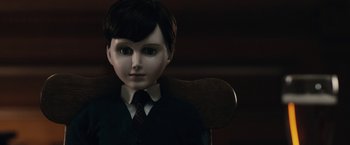 Movie still from “The Boy” (2016), directed by William Brent Bell – A creepy doll sitting on a chair in a dark room; Close Up shot, Over the shoulder angle