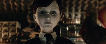 Movie still from “The Boy” (2016), directed by William Brent Bell – A creepy looking doll wearing a suit and necktie; Close Up shot, Low angle